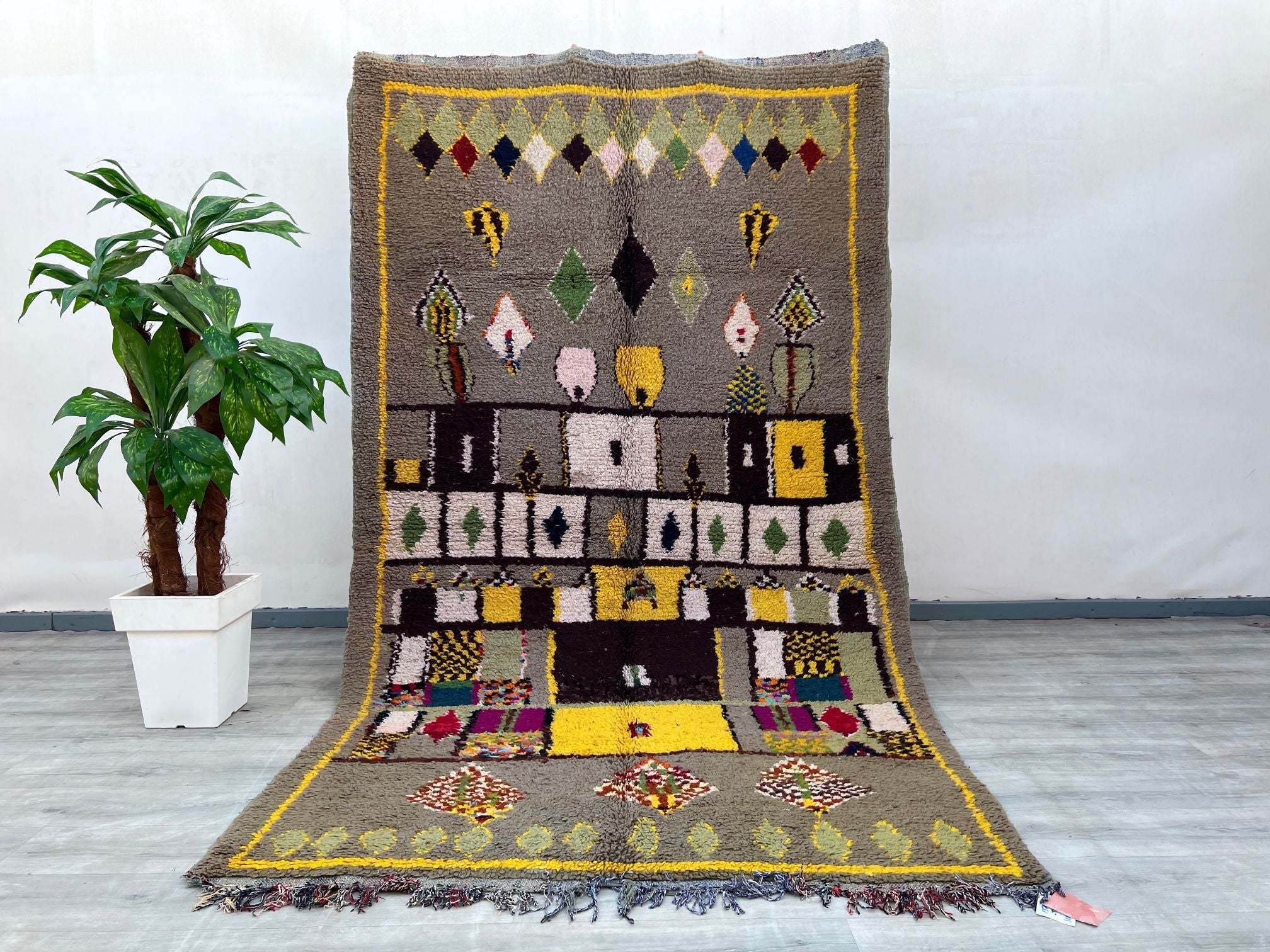 Discover the beauty of a handmade Moroccan rug with this 6x10 ft vintage Boujad carpet, a masterpiece of Berber tribal artistry. Woven from premium wool, this Beni Ourain-style rug features bold geometric patterns and a distressed finish for a rustic appeal. The neutral and colorful accents make it versatile for bohemian, Scandinavian, or eclectic interiors. Ideal as an area rug in high-traffic spaces, its durable flatweave construction ensures longevity. Each knot tells a story of Moroccan heritage, with A