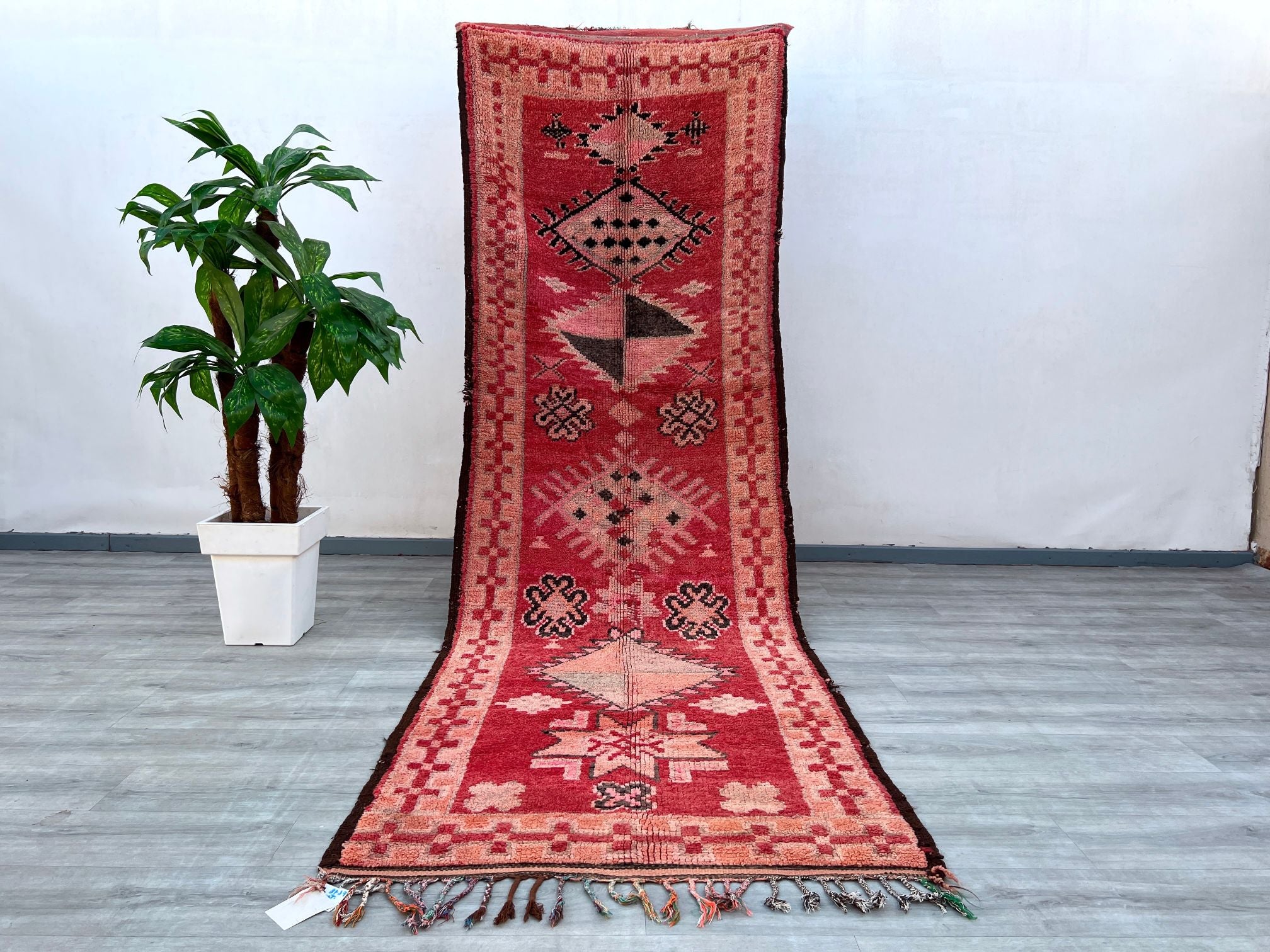 Discover the allure of this antique Moroccan runner rug, a stunning handwoven Berber carpet that exudes vintage character. With dimensions of 3.7 ft x 11.5 ft, this long, narrow rug is perfect for hallways, staircases, or as a bohemian area rug in eclectic spaces. The deep red and earthy tones blend with faded geometric motifs, reflecting the artistry of traditional tribal weaving. Made from natural wool, this distressed vintage rug offers both durability and softness underfoot, while its timeworn patina ad