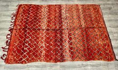 A 6x10 ft handmade Moroccan rug blending tribal Berber artistry with functional elegance. This wool Boujaad or Azilal carpet features a red and white geometric design, hand-knotted by artisans using age-old techniques. The bohemian runner suits high-traffic areas like hallways or living rooms, offering both resilience and softness underfoot. Its vintage distressed finish adds character, while the neutral and bold hues complement eclectic, Scandinavian, or global decor styles. Each rug tells a story through