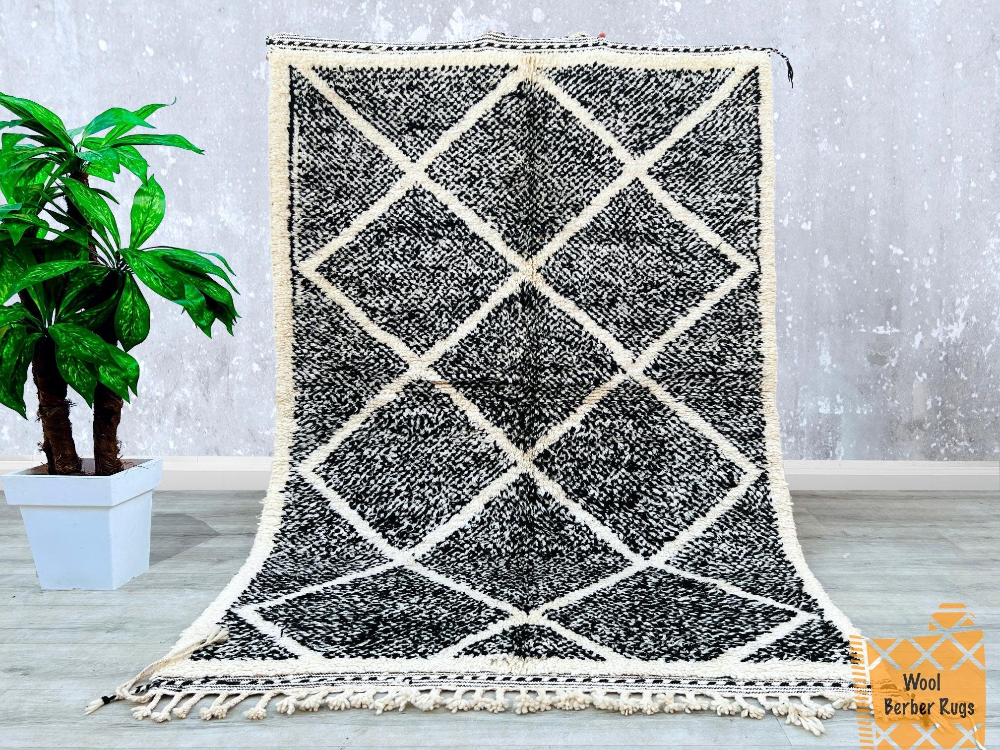Bring a touch of Moroccan heritage into your home with this stunning black and white Beni Ourain rug. Handwoven by skilled artisans, this Berber carpet showcases a striking diamond pattern, adding a bold yet sophisticated statement to any space. Made from premium sheep wool, it offers softness and durability, perfect for living rooms, bedrooms, or dining areas. The tribal-inspired design complements modern, rustic, and eclectic interiors. Each rug is unique, with slight variations that highlight its handmad