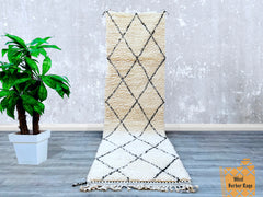 Bring timeless elegance to your home with this hand-knotted Moroccan Beni Ourain runner rug. Measuring 2.7 FT x 10.0 FT, this Berber wool carpet showcases a vintage black and white tribal motif, perfect for hallways, living rooms, or bedrooms. Each rug is individually handmade, ensuring a unique piece with slight variations that highlight its artisanal craftsmanship. The premium wool material offers a soft, cozy feel while being durable enough for daily use. Whether you're decorating a boho, Scandinavian, o