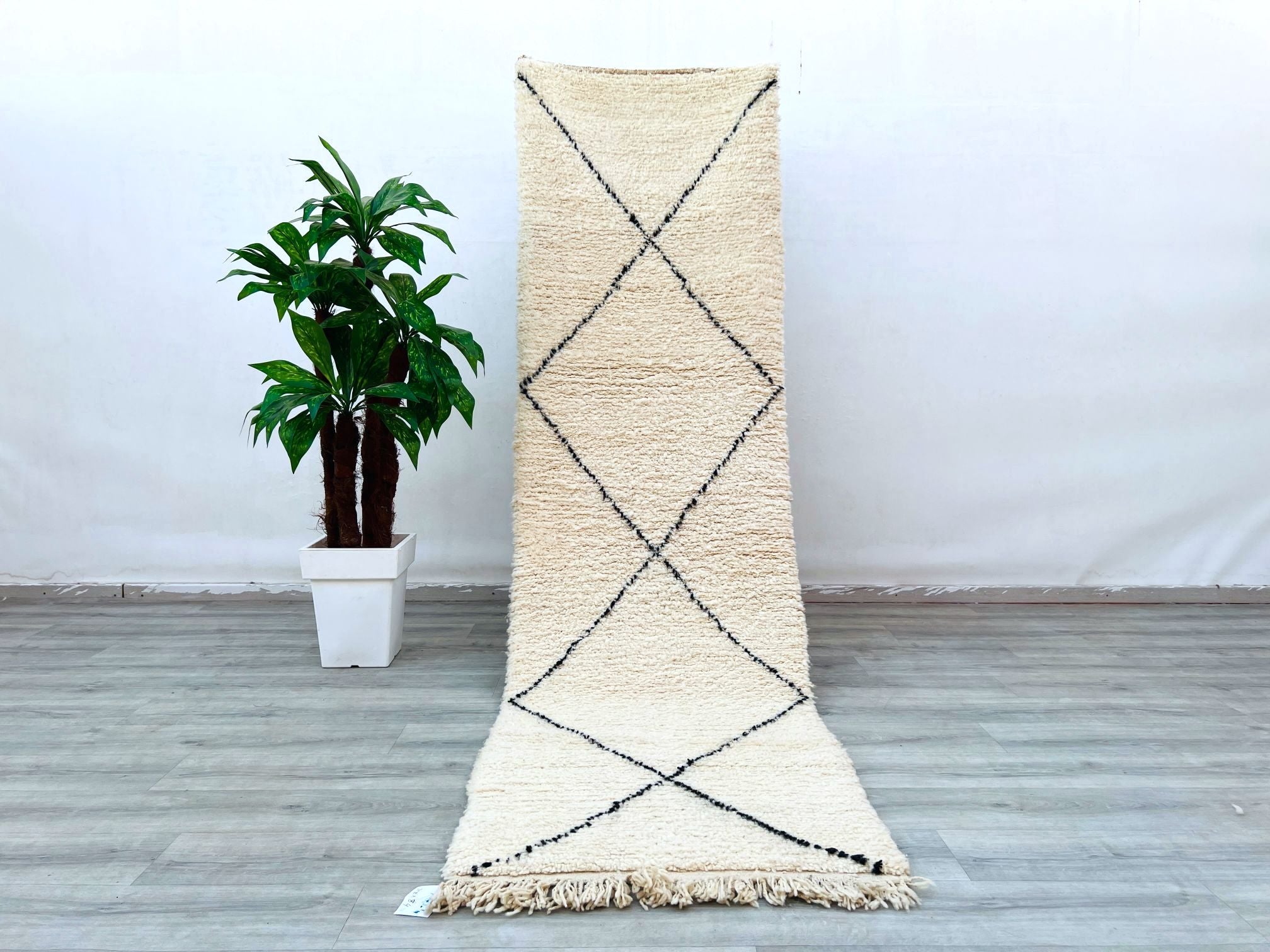 Enhance your home with a handmade Beni Ourain runner rug, crafted by Moroccan artisans using traditional techniques. This long hallway runner (approx. 3x10 FT) features a soft wool texture with classic black-and-white tribal designs, adding warmth and character to any space. The natural undyed wool ensures a hypoallergenic and sustainable choice. Perfect for high-traffic areas, this durable yet cozy Berber carpet works well in modern, Scandinavian, or eclectic interiors. Its versatile neutral tones compleme