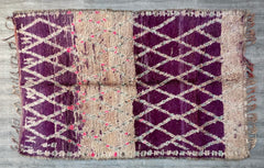 Bring a touch of global charm into your home with this authentic Moroccan Berber rug, a bohemian vintage floor covering crafted with care. Featuring a purple and multicolored abstract design, this handmade wool rug is a celebration of traditional weaving techniques. Ideal for boho home decor, it enhances living rooms, bedrooms, or entryways with its rich textures and vibrant hues. The vintage tribal rug is both durable and soft, offering comfort underfoot while adding artistic flair. Whether layered or used