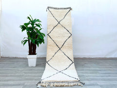 Elevate your home decor with this authentic Beni Ourain Moroccan runner rug, a hand-knotted wool masterpiece designed for hallways, kitchens, or bedrooms. The soft, durable wool ensures long-lasting quality, while the neutral black-and-white tribal patterns blend seamlessly with modern, boho, or minimalist interiors. Measuring 2.7 ft x 10 ft, this vintage Berber carpet is eco-friendly and ethically handmade, preserving traditional weaving techniques. Its high-pile texture adds warmth and coziness, making it