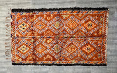 Bring rustic elegance into your space with authentic Moroccan wool rugs, showcasing bohemian vintage aesthetics. These handwoven carpets feature intricate diamond and abstract designs in earthy orange and red tones. Ideal for layering or as standalone statement pieces, they enhance living rooms, bedrooms, or entryways. The natural wool texture ensures softness underfoot while maintaining durability. A perfect choice for those seeking artisanal, culturally rich decor with a timeless appeal.