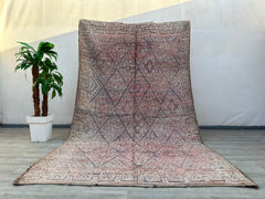 Enhance your décor with an authentic vintage Beni Mguild rug, a stunning example of Moroccan craftsmanship. This handmade wool rug features a rich blend of faded pinks, creams, and warm neutrals, creating a soft yet vibrant aesthetic. The tribal Berber designs reflect centuries-old weaving traditions, making each piece unique. Perfect for adding texture and warmth to modern, bohemian, or rustic interiors, this vintage Moroccan carpet is both durable and luxurious. Whether placed in a living room, bedroom, o