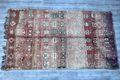 Discover the allure of Moroccan craftsmanship with this authentic vintage Boujaad rug, a handwoven tribal floor cover that exudes rustic elegance. Made from natural wool, this distressed Berber rug features a captivating geometric pattern, blending earthy reds, soft creams, and muted blues for a versatile aesthetic. Its durable, high-pile construction offers both comfort and longevity, making it perfect for high-traffic areas. Whether draped over a sofa, layered in a boho bedroom, or styled in a modern livi