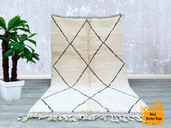 Elevate your decor with a black and white Moroccan wool rug, featuring a classic Berber tribal design. Hand-knotted from natural wool, this rug offers a plush, high-pile texture for unmatched comfort. The bold diamond and lozenge patterns create a striking contrast, making it a versatile statement piece for modern or vintage-inspired interiors. Whether used as a living room centerpiece, bedroom accent, or boho-chic floor covering, this rug adds texture, warmth, and cultural charm. Each rug is handmade, ensu