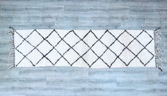 Elevate your decor with this handwoven Moroccan Beni Ourain runner rug, a vintage Berber carpet made from premium natural wool. Sized at 2.7 FT x 10.2 FT, this long hallway runner showcases classic black-and-white tribal designs, perfect for boho, farmhouse, or modern interiors. Each rug is individually handmade, ensuring a unique, artisanal touch. The plush wool pile provides softness underfoot, while the durable weave ensures longevity. Whether placed in a living room, bedroom, or entryway, this Moroccan