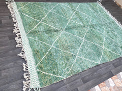 Infuse your home with bohemian elegance using this stunning handmade Moroccan Berber rug. The rich green color and intricate diamond patterns create a captivating visual appeal, perfect for adding depth to any room. Woven from natural wool, this rug is soft, resilient, and eco-conscious, making it a great choice for sustainable home decor. The traditional tribal designs pay homage to centuries-old weaving techniques, ensuring a one-of-a-kind piece. Whether placed in a living room, bedroom, or hallway, this