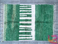 Elevate your interior with this bohemian green Moroccan rug, featuring a hand-knotted tribal design in luxurious natural wool. The rich green hues and intricate patterns make it a versatile decor piece, blending seamlessly with vintage, contemporary, or global-inspired styles. Handcrafted by Berber artisans, this eco-friendly rug offers both softness and durability, ideal for high-traffic areas. Whether used as a living room centerpiece or a bedroom accent, this authentic handmade carpet adds warmth and art
