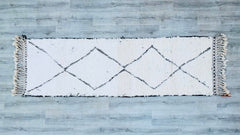 Transform your home with this bohemian Moroccan runner rug, a stunning handwoven piece measuring 3x10 ft. Featuring classic Beni Ourain patterns, this Berber-style rug is crafted from natural wool, offering a plush, cozy feel underfoot. The neutral palette and tribal designs make it a versatile addition to any space—hallways, dining areas, or beside the bed. Each rug is uniquely handmade, ensuring no two are alike, with slight variations that highlight its artisanal beauty. Durable, hypoallergenic, and sust