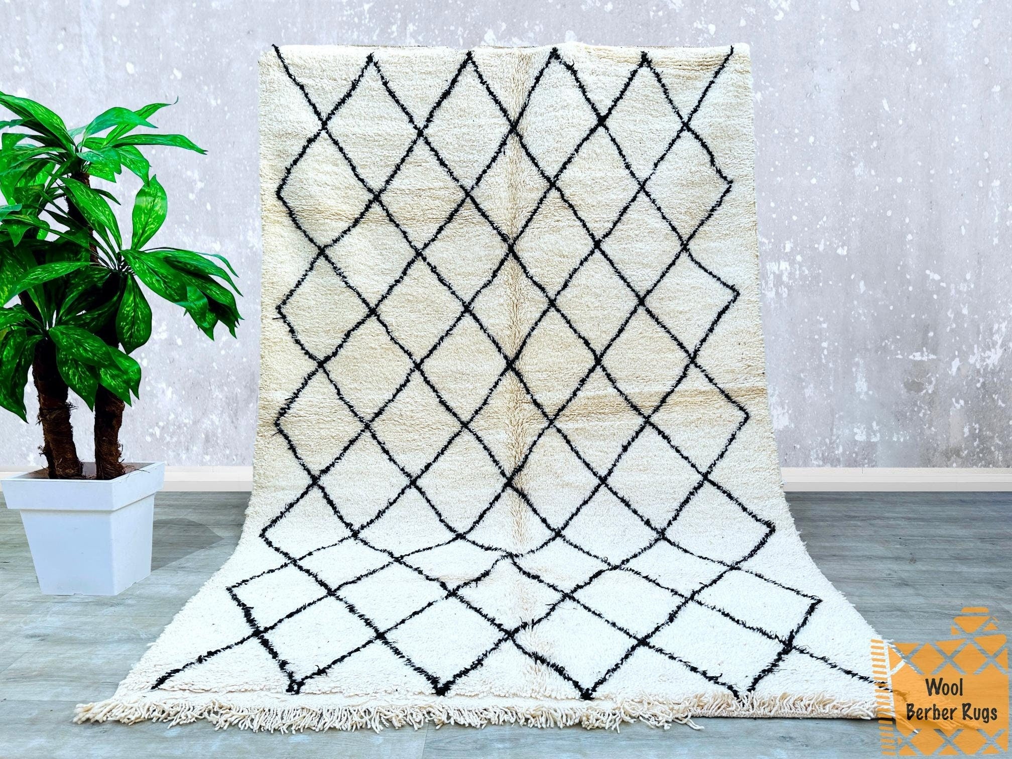 Bring warmth and character to your home with this handwoven Moroccan wool rug, inspired by traditional Berber designs. Featuring a soft, high-pile texture and a neutral cream-and-black pattern, this versatile rug complements boho, minimalist, and contemporary interiors. Made from natural wool, it offers durability and a luxurious feel, ideal for high-traffic areas. The intricate tribal motifs tell a story of heritage and craftsmanship, making each piece one-of-a-kind. Perfect for layering in living rooms, u