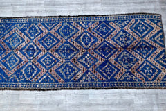 Elevate your space with this expansive vintage Moroccan rug, a masterpiece of Berber weaving. At nearly 14 feet long, this 6x13 ft rug features a captivating mix of geometric motifs and a muted, timeworn palette, ideal for creating a cozy, layered look. Handmade from pure sheep’s wool, it’s both soft and hardwearing, suitable for floors, walls, or even as a statement bedspread. The rug’s faded hues and irregular stitching highlight its authentic, artisanal origins, offering a touch of wanderlust to any room