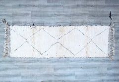 Enhance your space with a genuine Moroccan Berber rug, featuring the iconic Beni Ourain tribal patterns. These handwoven wool rugs are prized for their softness, warmth, and artisanal imperfections, making each one a unique work of art. Ideal as long runners (2.9x12.5 ft) or large area rugs (7x9 ft), they suit bohemian, Scandinavian, or mid-century interiors. The neutral black-and-white palette pairs well with bold or minimalist décor. Made from natural, undyed wool, these eco-friendly carpets are free from