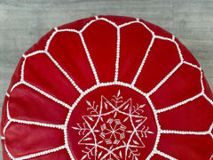 Add a bohemian flair to your home with our Moroccan leather pouf. Handcrafted in Marrakech, this round leather ottoman features natural goat leather with traditional embroidery, creating a unique, artisanal look. Lightweight and portable, it works as a footstool, side table, or floor seat. Choose between stuffed or unstuffed options to customize firmness. Perfect for boho, eclectic, or global-inspired interiors, this eco-friendly pouf is filled with recycled materials. Free worldwide shipping available. Tra