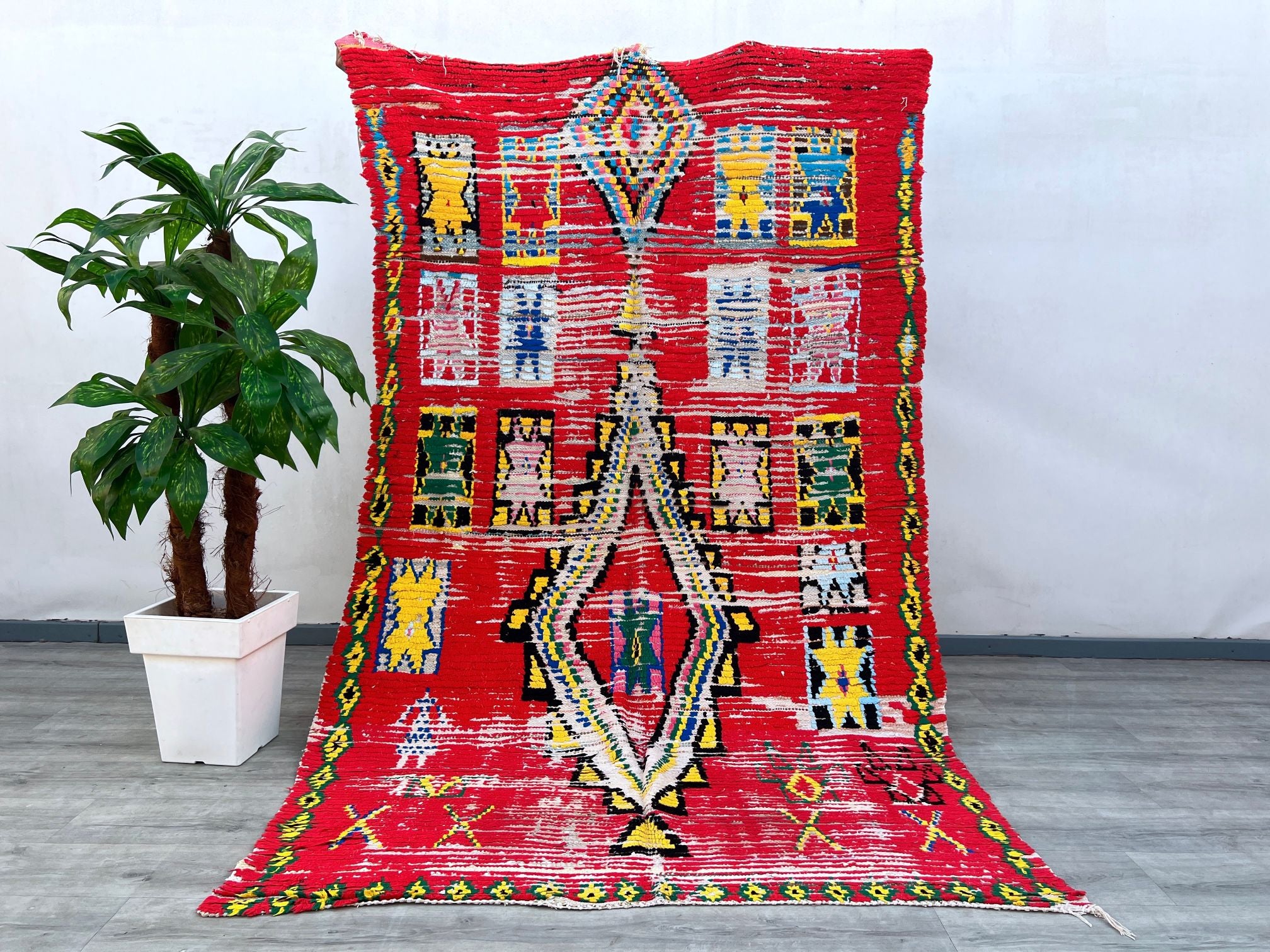 Elevate your space with this colorful vintage Moroccan rug, handcrafted in the traditional Boujaad style. Featuring bold reds, earthy tones, and playful geometric motifs, this rug embodies the rich artistry of Berber weaving. Each piece is unique, with slight variations that highlight its handmade authenticity. The plush wool construction ensures both comfort and longevity, making it ideal for high-traffic areas. Whether used as an area rug, wall hanging, or boho-chic accent, this Moroccan Berber carpet add