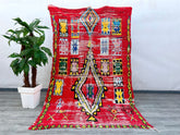 Elevate your space with this colorful vintage Moroccan rug, handcrafted in the traditional Boujaad style. Featuring bold reds, earthy tones, and playful geometric motifs, this rug embodies the rich artistry of Berber weaving. Each piece is unique, with slight variations that highlight its handmade authenticity. The plush wool construction ensures both comfort and longevity, making it ideal for high-traffic areas. Whether used as an area rug, wall hanging, or boho-chic accent, this Moroccan Berber carpet add