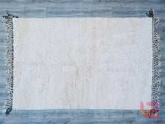 Discover the beauty of a custom wool Beni Ourain area rug, meticulously crafted for understated elegance. This handmade Moroccan rug features a solid white design with a plush, high-pile finish, offering unmatched comfort underfoot. Woven using traditional Berber techniques, each piece showcases slight imperfections, highlighting its artisanal authenticity. The breathable wool material ensures year-round comfort, while the neutral white hue effortlessly brightens any room. Perfect for layering or as a focal
