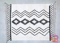 Add a boho-chic touch to your space with a custom wool Moroccan rug, meticulously handmade by Berber weavers. This versatile area rug showcases a neutral ivory and black design, blending seamlessly with any decor style. The plush, high-pile wool offers luxurious comfort, while the intricate tribal motifs tell a story of heritage. Whether you prefer a vintage distressed look or a clean modern aesthetic, this hand-knotted Moroccan carpet is a timeless investment. Enjoy free shipping and a one-of-a-kind piece