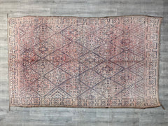 Discover the rustic charm of a faded vintage Boujaad rug, a true masterpiece of Moroccan textile art. Woven from natural wool, this handmade Berber rug features a distressed, time-worn look with earthy reds, faded blues, and warm neutrals. The geometric and tribal motifs add a bohemian flair, making it a versatile choice for eclectic, farmhouse, or global-inspired interiors. As an authentic vintage Moroccan rug, it carries the essence of traditional craftsmanship, offering both durability and timeless beaut