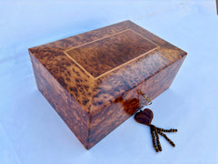 Enhance your jewelry collection with this beautifully handcrafted wooden jewelry box featuring a secure lock. Made from luxurious burl wood, this decorative box showcases intricate natural grain patterns, adding a touch of sophistication to any dresser or vanity. The spacious interior includes two levels of storage, perfect for organizing rings, necklaces, earrings, and watches. The hinged lid and durable latch ensure your valuables stay safe, while the polished finish highlights the wood’s rich texture. Id