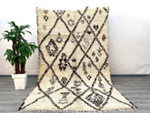 A vintage-inspired Berber wool rug that brings the soul of Morocco into your home. Woven from natural, undyed lamb wool, this Beni Ourain-style carpet features a high-pile shaggy texture for ultimate comfort. The organic ivory-and-charcoal patterns are subtly asymmetrical, celebrating the artistry of handmade imperfections. Ideal for high-traffic areas, the sturdy wool resists wear while maintaining its plush feel. This ethically sourced rug supports women-led cooperatives in rural Morocco, empowering tradi