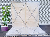 Discover the timeless beauty of a handmade Moroccan Beni Ourain rug, crafted by Berber artisans using 100% pure wool. This authentic vintage rug features a soft, plush texture and a minimalist black-and-white diamond pattern, perfect for boho, modern, or rustic interiors. Available in custom sizes, this luxurious Berber carpet adds warmth and elegance to any space—ideal for living rooms, bedrooms, or home decor. Shop bohemian rugs online with free shipping options. A sustainable, ethically sourced piece tha
