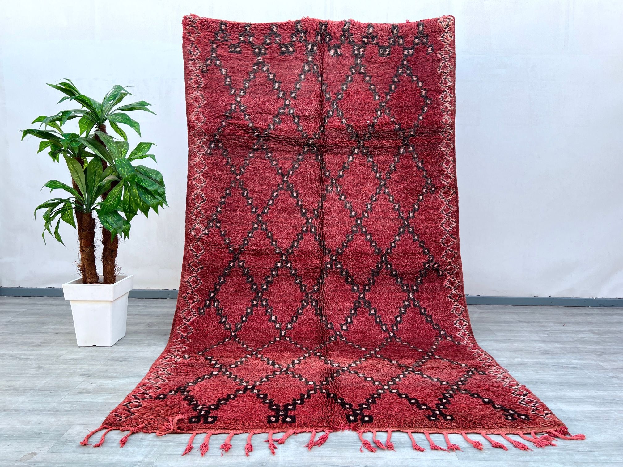 Elevate your decor with this exquisite handmade Moroccan Boujad rug, featuring bold tribal motifs and a striking red and black diamond design. Woven using centuries-old techniques, this vintage carpet embodies the essence of Berber culture with its plush texture and intricate detailing. The distressed finish enhances its antique appeal, making it a perfect fit for boho, mid-century, or global-inspired interiors. Crafted from premium wool, it offers durability and softness underfoot. Ideal as a statement flo