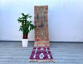 Elevate your décor with this handwoven Berber runner rug, a stunning vintage Moroccan piece measuring 2.3 x 10.9 ft. Crafted from natural wool, it boasts a soft, shaggy texture and a colorful abstract pattern in hues of purple, pink, and cream. The tribal Boujaad design reflects centuries-old weaving traditions, making it a statement piece for boho, eclectic, or minimalist interiors. Ideal for high-traffic areas, this durable yet cozy runner adds warmth to hallways, bedrooms, or entryways. Each rug is one-o