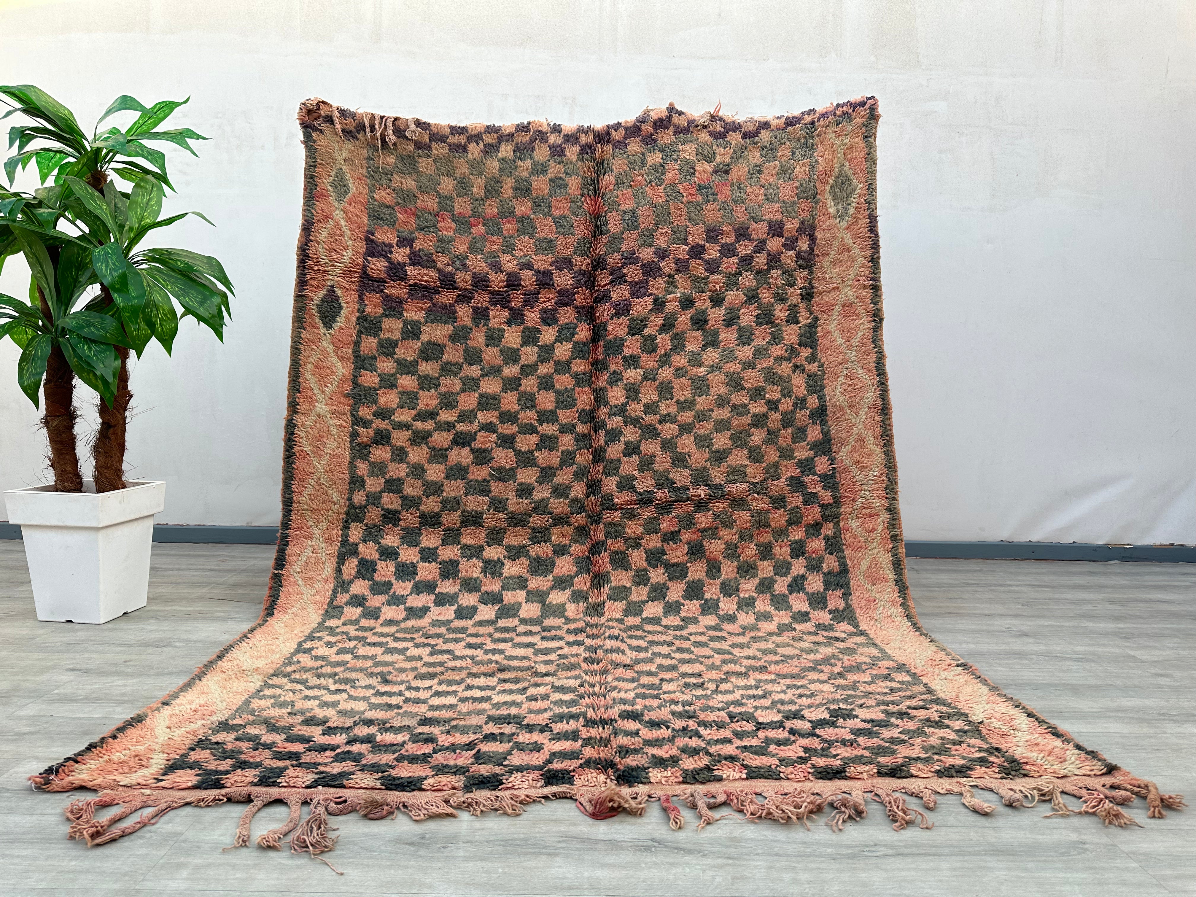 Enhance your space with this vibrant vintage checkered Moroccan rug, showcasing a beautiful blend of pink, brown, and black tribal patterns. Crafted by skilled artisans, this Berber-style rug features a mix of geometric motifs and a plush, textured feel. Ideal for layering or as a standalone statement, it adds warmth and character to bedrooms, living rooms, or dining areas. The distressed, wabi-sabi aesthetic gives it a well-loved, timeless appeal, perfect for those who appreciate handmade, one-of-a-kind de