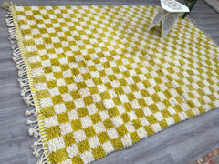 Add a pop of artisanal charm to your home with this handwoven Moroccan Azilal rug, featuring a vibrant checkered pattern in yellow, white, and earthy tones. Made from premium sheep wool, this Bohemian-style rug is hand-knotted by skilled Berber weavers, ensuring a unique, textured finish. The tribal geometric design brings a global boho vibe to living rooms, bedrooms, or entryways, while the plush high pile offers unmatched comfort. Ideal for eclectic, farmhouse, or modern interiors, this checkered Moroccan