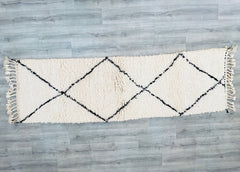 Elevate your hallway or living space with this authentic Moroccan Beni Ourain runner rug, handwoven by Berber artisans. Measuring 2.9 x 8.5 feet, this long, narrow rug features a soft wool blend in timeless white and blue geometric patterns, inspired by traditional tribal designs. Perfect for high-traffic areas, the durable, plush texture adds warmth and boho charm to any home. Each rug is hand-knotted, ensuring a unique, artisanal touch. The neutral tones blend seamlessly with modern, rustic, or eclectic d