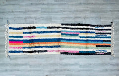 Upgrade your space with a luxurious Moroccan runner rug, featuring a 3.0 FT x 10.1 FT Berber-style weave in soft, high-pile wool. This hand-knotted carpet boasts vibrant dyes and tribal geometric patterns, reflecting the artistry of Moroccan craftsmanship. Perfect for hallways, bedrooms, or dining areas, its neutral and multicolored options suit any palette. The Boucherouite-inspired texture or Beni Ourain motifs add depth to contemporary or rustic interiors. Eco-friendly and hypoallergenic, this fair-trade