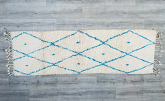 Enhance your home with this exquisite handmade Moroccan runner rug, featuring a stunning blue and white geometric design inspired by traditional Beni Ourain weaving techniques. Crafted from 100% natural wool, this 2.5 x 8 ft hallway runner brings warmth, texture, and a touch of bohemian elegance to any space. Each rug is handwoven by Berber artisans, ensuring a unique, vintage-inspired piece with slight variations that highlight its authenticity. Perfect for entryways, corridors, or beside the bed, this sof