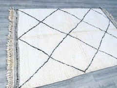 Bring the charm of Moroccan craftsmanship into your home with this handwoven Berber rug. Made from soft, high-quality wool, it showcases a minimalist black-and-white design, perfect for Scandinavian, boho, or rustic interiors. The plush, durable weave ensures comfort underfoot, making it ideal for high-traffic areas. Each rug is individually crafted, featuring subtle variations that highlight its artisan-made authenticity. Whether used as a living room centerpiece, bedroom accent, or hallway runner, this Be