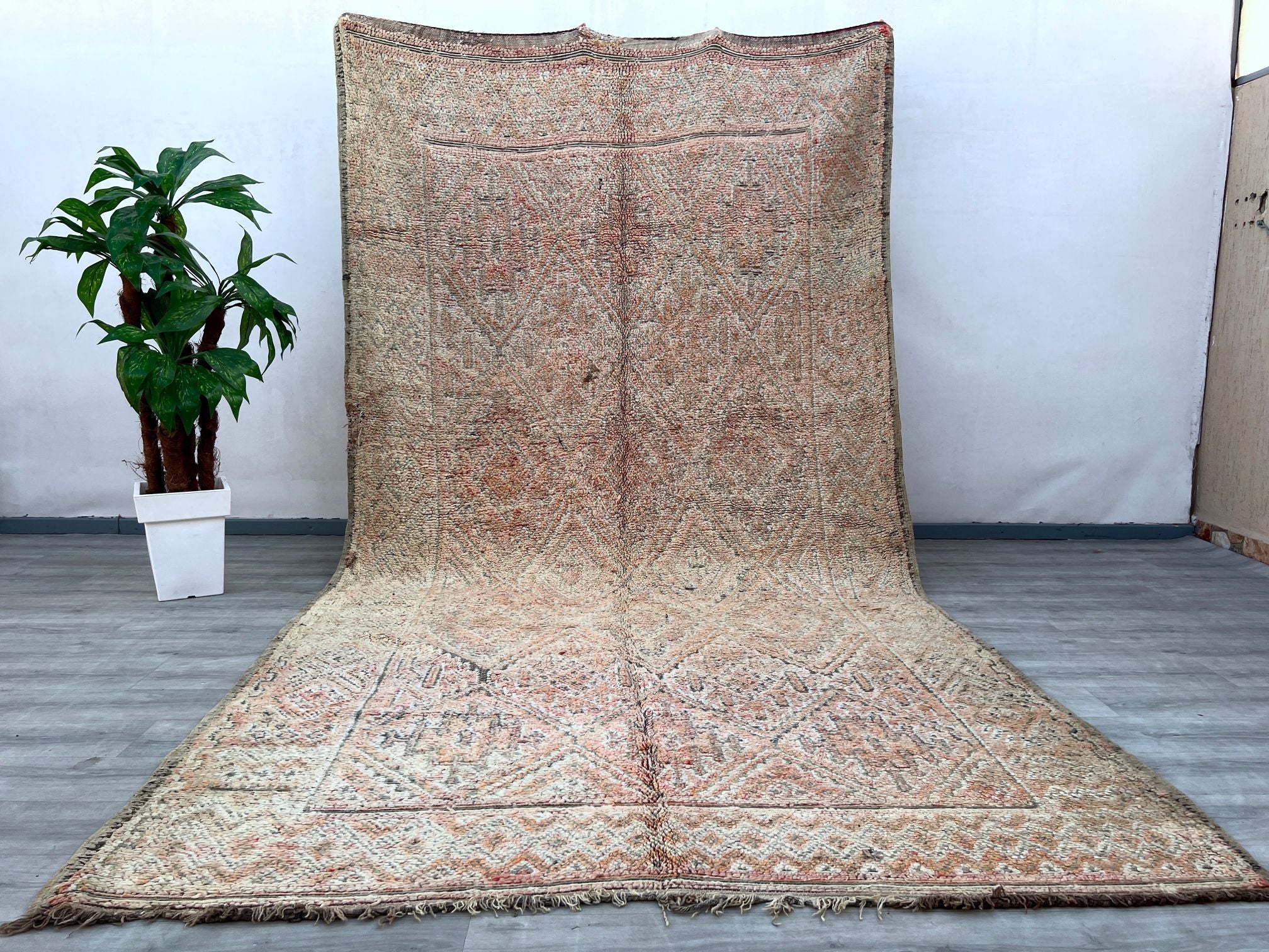 Transform your home into a cozy sanctuary with this large vintage Moroccan rug, featuring a stunning distressed design and a warm, faded palette. Handwoven by Berber tribes using traditional techniques, this luxurious wool rug showcases intricate geometric motifs that add depth and texture to any room. Ideal for spacious living areas, bedrooms, or even as a statement hallway runner, this boho-inspired carpet brings a rustic yet refined charm. The natural fibers ensure durability, while the soft pile offers