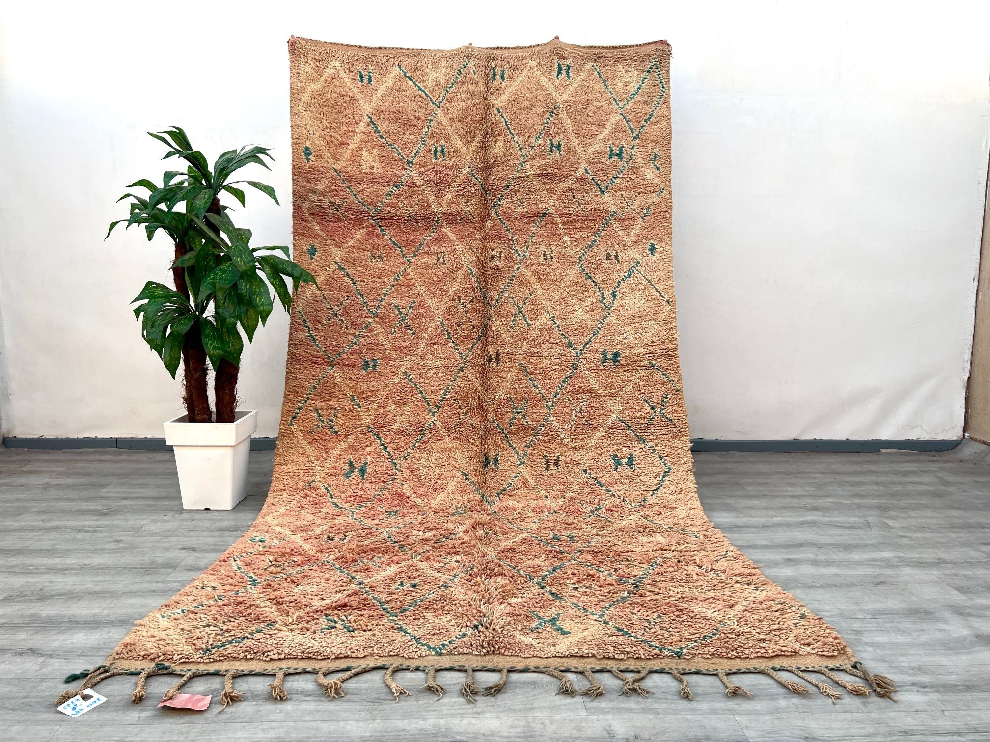Elevate your decor with this handmade vintage Moroccan Boujaad rug, a stunning 6x11-foot masterpiece crafted by skilled Berber weavers. Featuring tribal geometric patterns in warm, faded hues, this rug embodies the essence of Moroccan heritage and artisanal tradition. Woven from premium wool, it offers both durability and a luxuriously soft texture, ideal for high-traffic areas. The Boujaad style is celebrated for its asymmetrical designs and symbolic motifs, reflecting centuries of nomadic craftsmanship. P