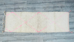 Upgrade your décor with this authentic handmade Moroccan runner rug, a 2.7 x 8.3 ft Berber wool carpet in a delicate pink and white color scheme. Designed for both style and functionality, this vintage-inspired Beni Ourain rug features tribal diamond patterns and a plush, high-pile texture, making it ideal for high-traffic areas like hallways or living rooms. The natural wool fibers provide warmth and softness, while the neutral pink hues complement modern, boho, and eclectic interiors. Each rug is hand-kno