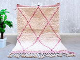 Elevate your interior with this beautiful pink Moroccan rug, inspired by the vibrant Azilal and Beni Ourain weaving traditions. Each piece is meticulously handwoven using natural wool, ensuring a soft yet durable texture. The abstract diamond patterns and geometric lines reflect authentic Berber artistry, creating a unique focal point for any room. Ideal for boho, eclectic, or modern interiors, this rug adds a pop of color while maintaining a neutral elegance. Its lightweight yet sturdy construction makes i