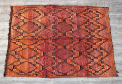 This authentic Moroccan Berber rug showcases a beautiful blend of tribal medallions and geometric motifs in deep rust, red, and blue tones. Handwoven using age-old techniques, each piece tells a story of heritage and craftsmanship. The thick, plush wool provides comfort and durability, while the distressed vintage look adds character and charm. Perfect for bohemian, rustic, or global-inspired interiors, this rug effortlessly elevates any space with its rich textures and cultural authenticity. Whether used a