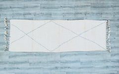 Infuse your home with Moroccan soul using this handwoven Beni Ourain runner rug. Crafted in the Berber tradition, this 3x9 ft wool carpet features a sumptuous high-pile texture and understated geometric designs, perfect for adding warmth to minimalist spaces. The natural ivory backdrop with contrasting tribal motifs creates a versatile accent for modern farmhouse, bohemian, or global-inspired decor. Made from premium sheep wool, it’s soft underfoot and built to last, with a hand-tied fringe for an artisanal