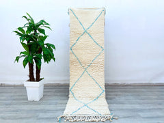 Bring timeless charm to your interiors with this vintage blue and white Moroccan Beni Ourain rug. Measuring 2.5 x 8 ft, this hand-knotted wool runner showcases intricate Berber motifs, blending traditional craftsmanship with modern boho style. The soft, high-pile wool ensures comfort underfoot, while the neutral tones effortlessly complement any décor—from Scandinavian to eclectic. Perfect for hallways, bedrooms, or dining areas, this authentic Moroccan carpet is ethically handmade by artisans using age-old
