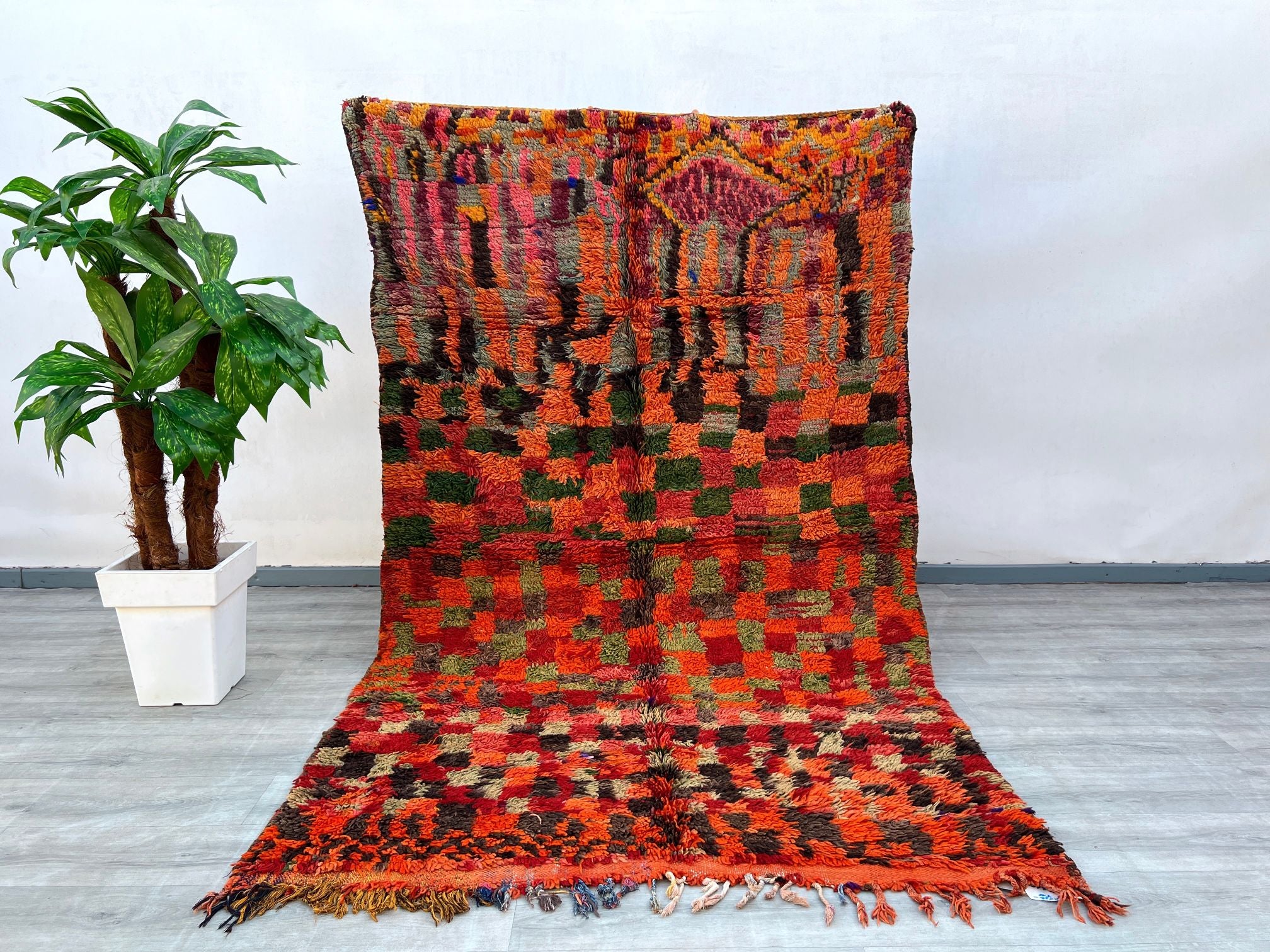 Bring warmth and history into your home with this hand-knotted vintage Moroccan rug, a true Berber masterpiece from the Boujad region. Its vibrant red hues and checkered geometric design reflect centuries-old weaving traditions, while the soft wool pile ensures comfort underfoot. Perfect for boho, rustic, or minimalist interiors, this rug adds texture and a pop of color. The slightly worn edges and organic imperfections highlight its authentic vintage appeal, making it a conversation starter. Whether layere