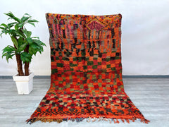 Bring warmth and history into your home with this hand-knotted vintage Moroccan rug, a true Berber masterpiece from the Boujad region. Its vibrant red hues and checkered geometric design reflect centuries-old weaving traditions, while the soft wool pile ensures comfort underfoot. Perfect for boho, rustic, or minimalist interiors, this rug adds texture and a pop of color. The slightly worn edges and organic imperfections highlight its authentic vintage appeal, making it a conversation starter. Whether layere