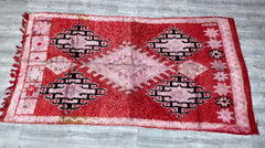 Elevate your decor with this handmade vintage Moroccan Berber rug, a 5x11 ft tribal carpet featuring authentic Boujaad craftsmanship. Woven by Berber women using traditional techniques, this old wool rug boasts intricate diamond patterns and a faded, earthy palette of reds, pinks, and neutrals. The slightly irregular edges and subtle wear highlight its one-of-a-kind vintage appeal, making it a conversation-starting centerpiece. Ideal for boho, mid-century, or global-inspired interiors, this durable yet plus