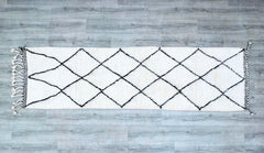 Elevate your space with this handmade Beni Ourain Moroccan Runner Rug, a stunning Berber carpet crafted from 100% natural wool. Measuring 2.6 ft x 9.7 ft, this vintage-bound hallway runner features the iconic tribal geometric patterns of Morocco’s Atlas Mountains. Each rug is hand-knotted by skilled artisans, ensuring durability and a plush, shaggy texture. The neutral ivory and charcoal tones blend seamlessly with boho, modern, and rustic interiors. Perfect for entryways, living rooms, or bedrooms, this au