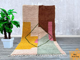 Elevate your space with this exquisite Moroccan Boujaad rug, blending pink, orange, and earthy tones in a mesmerizing geometric pattern. Handwoven by Berber artisans, this 9'5x6'5 ft (2.9x2 m) wool rug showcases the Bidouh tribal design, known for its bold colors and intricate motifs. The plush, high-pile texture provides unmatched comfort, making it ideal for cozy lounging areas or stylish boho decor. As a versatile statement piece, it complements neutral interiors while infusing warmth and global artistry