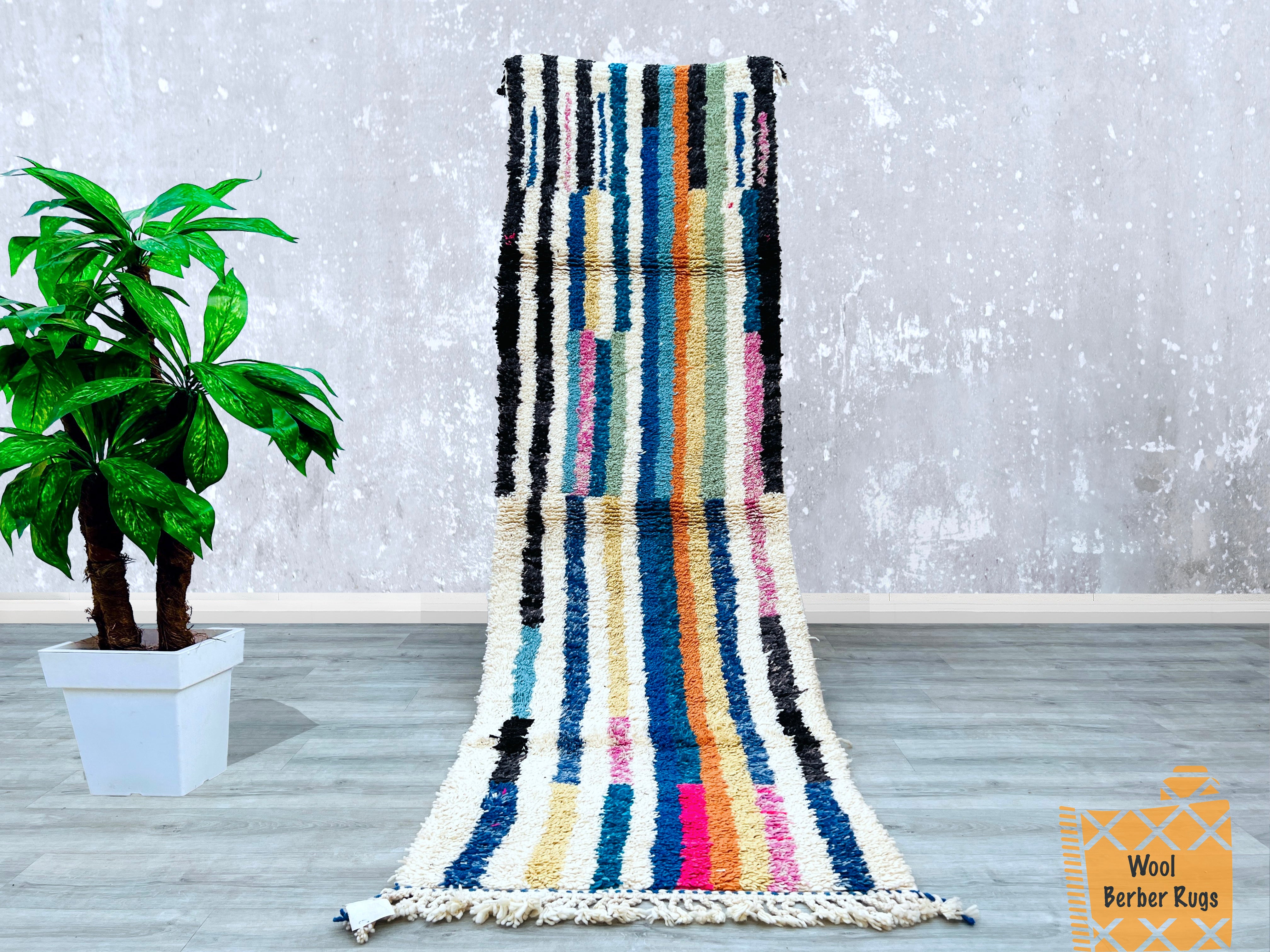 Bring global charm to your floors with this 3x10 FT Moroccan runner rug, showcasing a handwoven Beni Ourain pattern in bold, multicolored wool. Ideal for high-traffic areas, this durable hallway carpet blends Bohemian flair with traditional Berber craftsmanship. The intricate tribal motifs and plush texture make it a standout piece for minimalist or maximalist décor. Choose from vintage-bound finishes, Azilal-inspired designs, or custom color schemes to match your aesthetic. Each rug is ethically handmade,