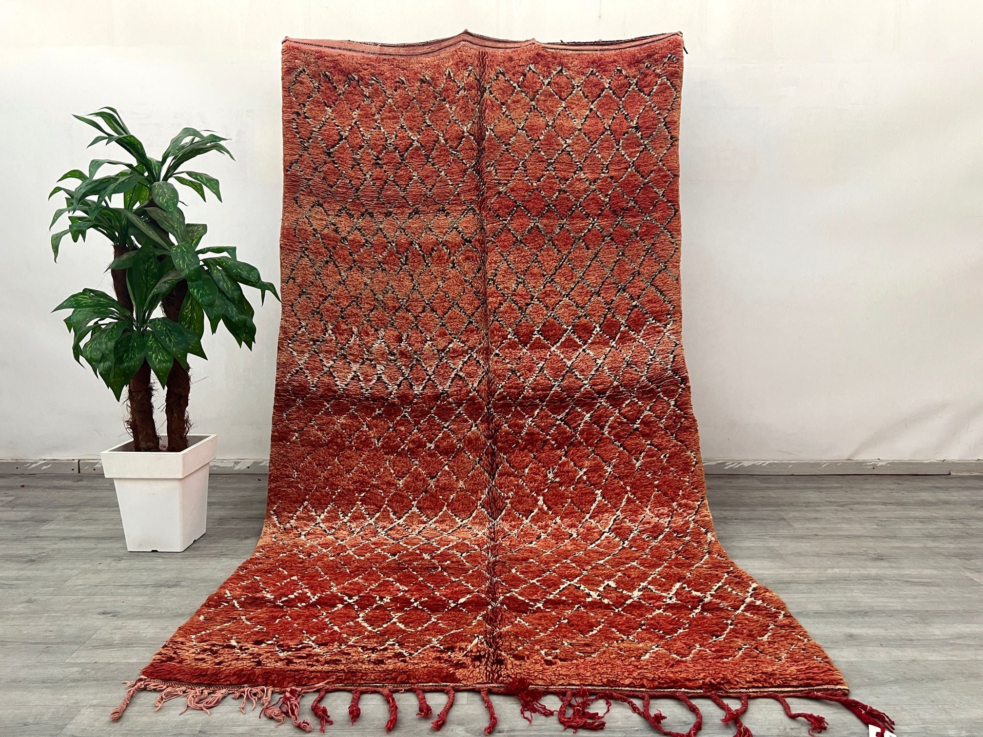 Elevate your home with this vintage 6x10 ft Moroccan rug, a handwoven Berber masterpiece from the Middle Atlas region. Made from natural wool, this Boujaad or Azilal tribal rug boasts a distressed, timeworn look with vibrant reds, creams, and blues. The hand-knotted technique ensures durability, while the organic diamond and zigzag patterns reflect centuries-old craftsmanship. Perfect for bohemian, farmhouse, or modern minimalist spaces, this rug adds texture and history underfoot. Its fair trade origins su